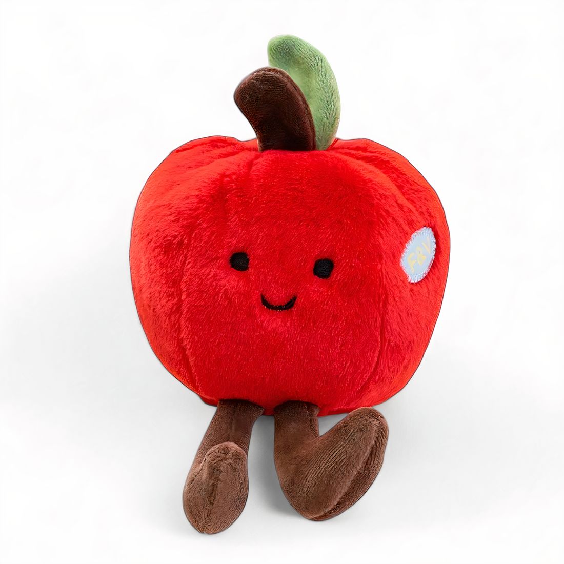 Peluche rosso a forma di mela con un sorriso, zampe marroni e un piccolo picciolo verde sulla testa, posato su sfondo bianco.