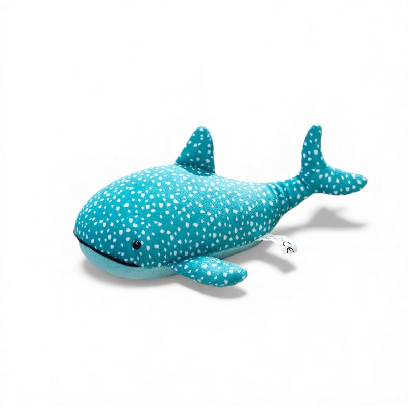 Peluche squalo balena blu turchese di circa 25 cm, ricoperta di piccoli pois bianchi, con pinne e coda arrotondate, pancia azzurra uniforme e piccolo occhio nero, posata da sola su sfondo bianco.