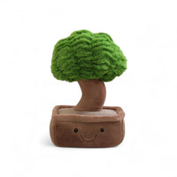 Peluche pianta kawaii a forma di bonsai sorridente con vaso marrone e fogliame verde, posato su sfondo bianco.