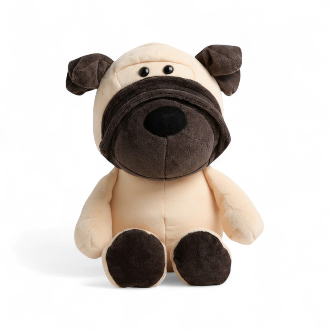 Peluche cane beige muso nero, orecchie cadenti, seduto, sguardo malizioso e zampe arrotondate su sfondo bianco.