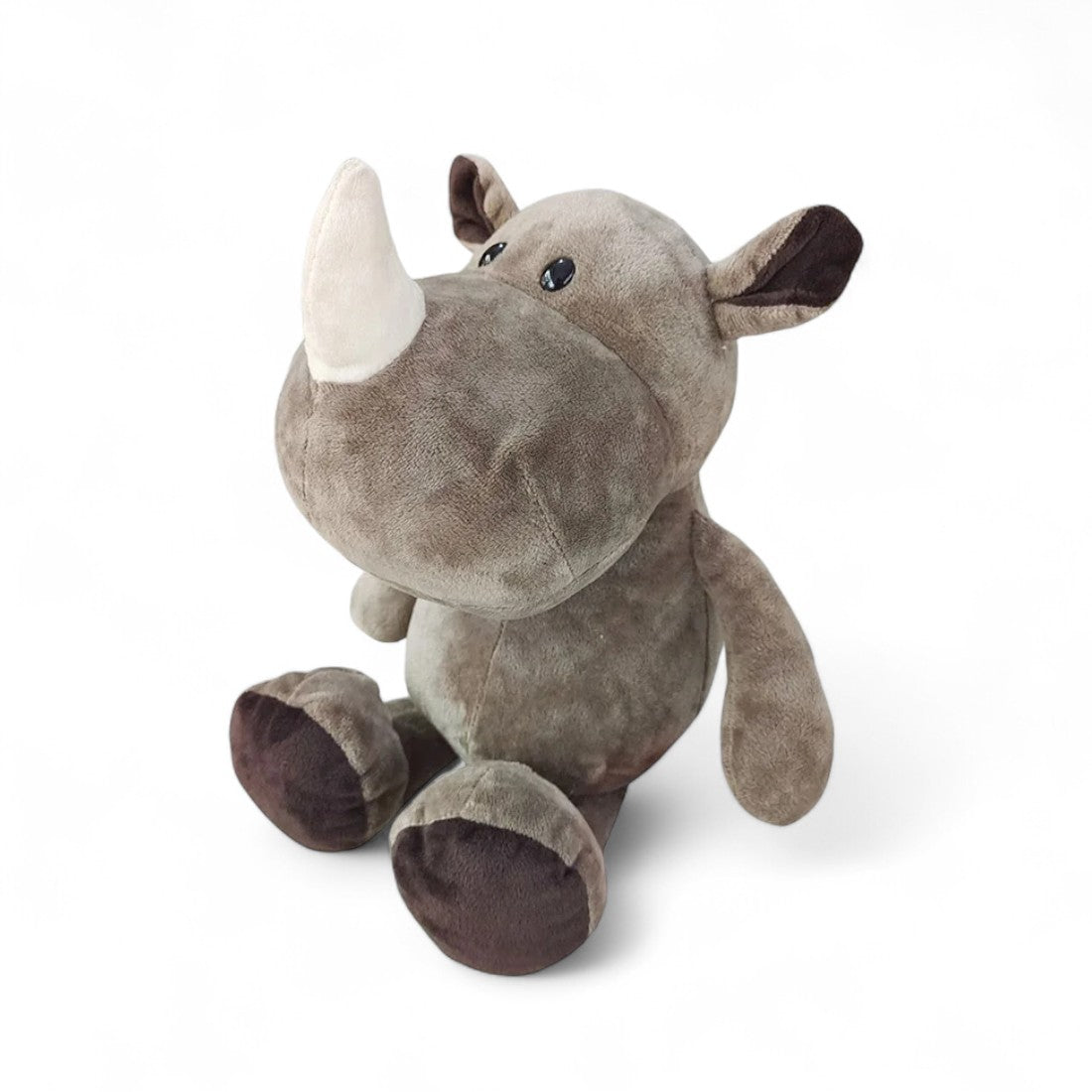 Rinoceronte di peluche grigio, muso largo, corno bianco morbido, seduto su sfondo bianco.
