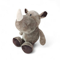 Rinoceronte di peluche grigio, muso largo, corno bianco morbido, seduto su sfondo bianco.