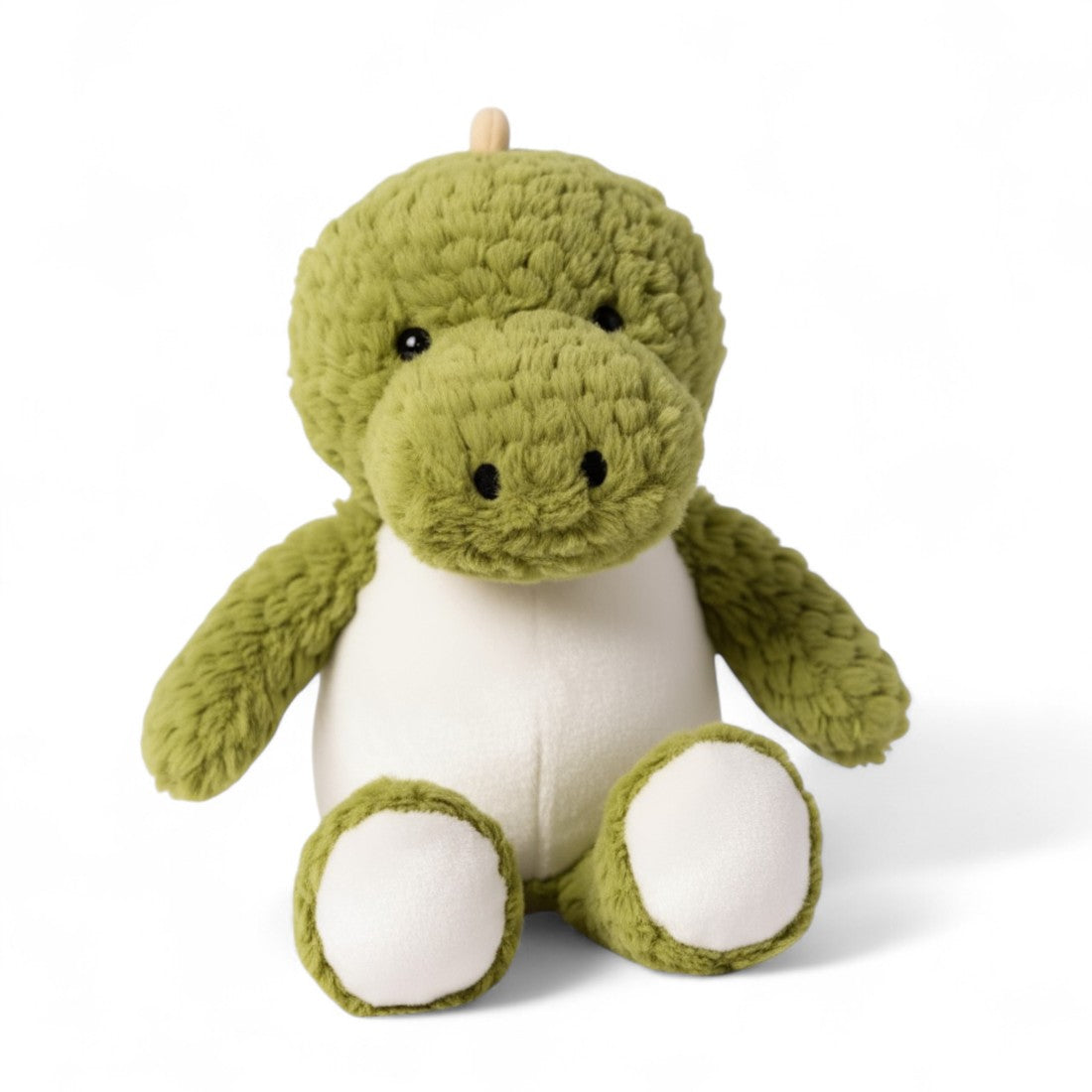 Peluche dinosauro verde, pancia bianca, musetto largo, occhi tondi ricamati, cresta giallo pallido sulla testa e sul dorso, forma seduta morbida, su sfondo bianco