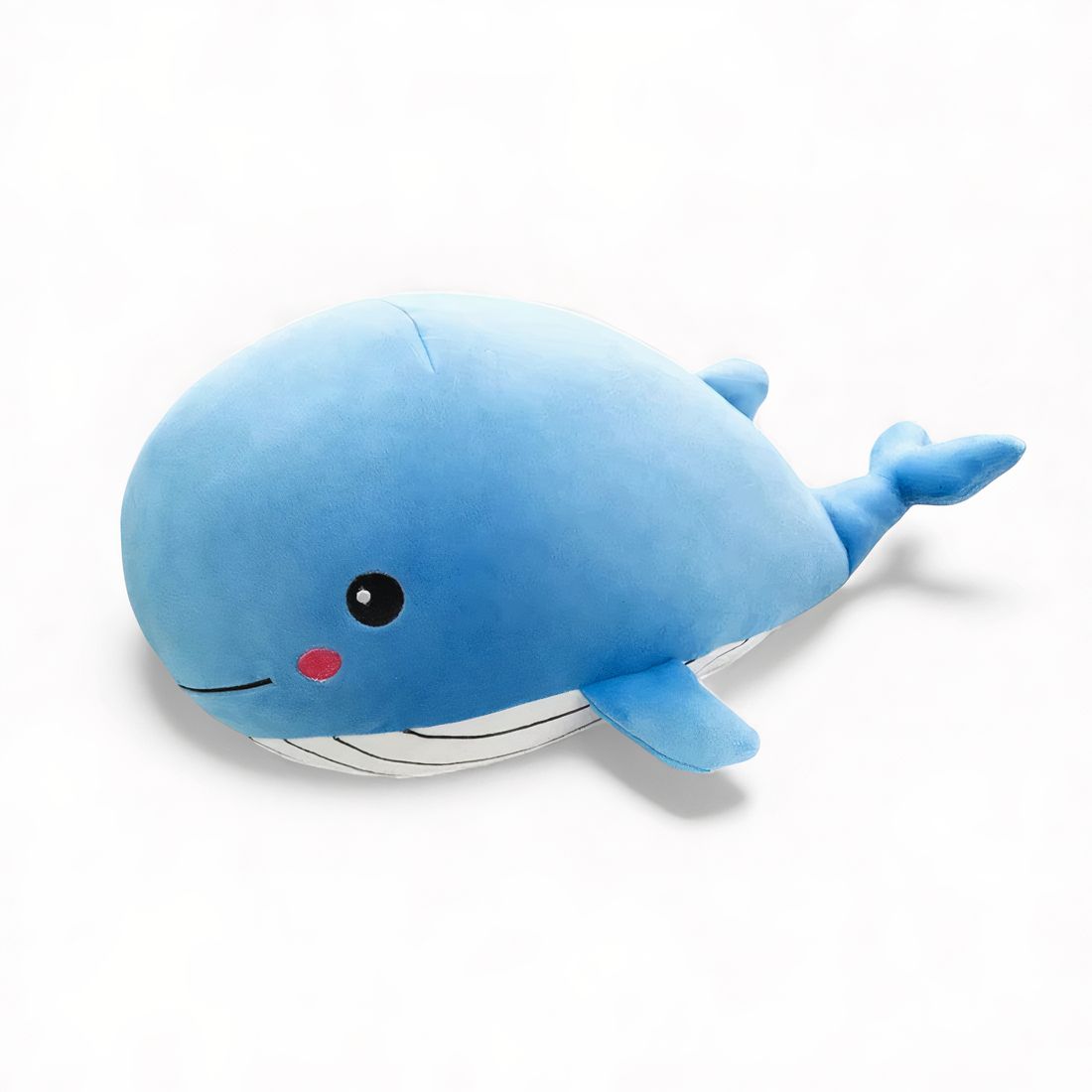 Peluche balena blu, allungata con pinne e coda morbide, guance rosa, posata su un divano o su sfondo bianco.