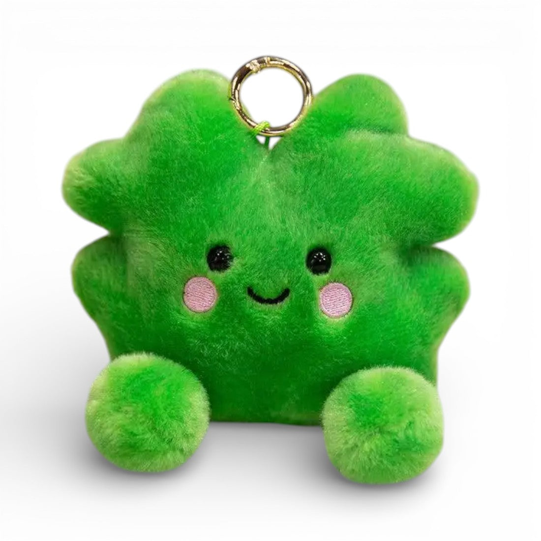 Peluche kawaii a forma di quadrifoglio verde vivo, grandi occhi neri brillanti, guance rosa tonde, sorriso tenero, molteplici foglioline soffici, due piccole zampe verdi paffute in basso, anello dorato sopra, su sfondo bianco.